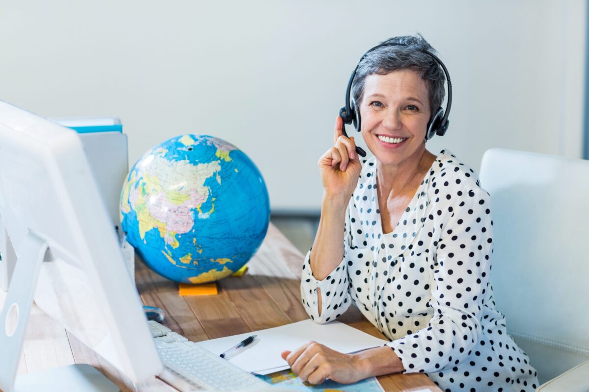 Smiling woman with headset teaching geography using a globe.