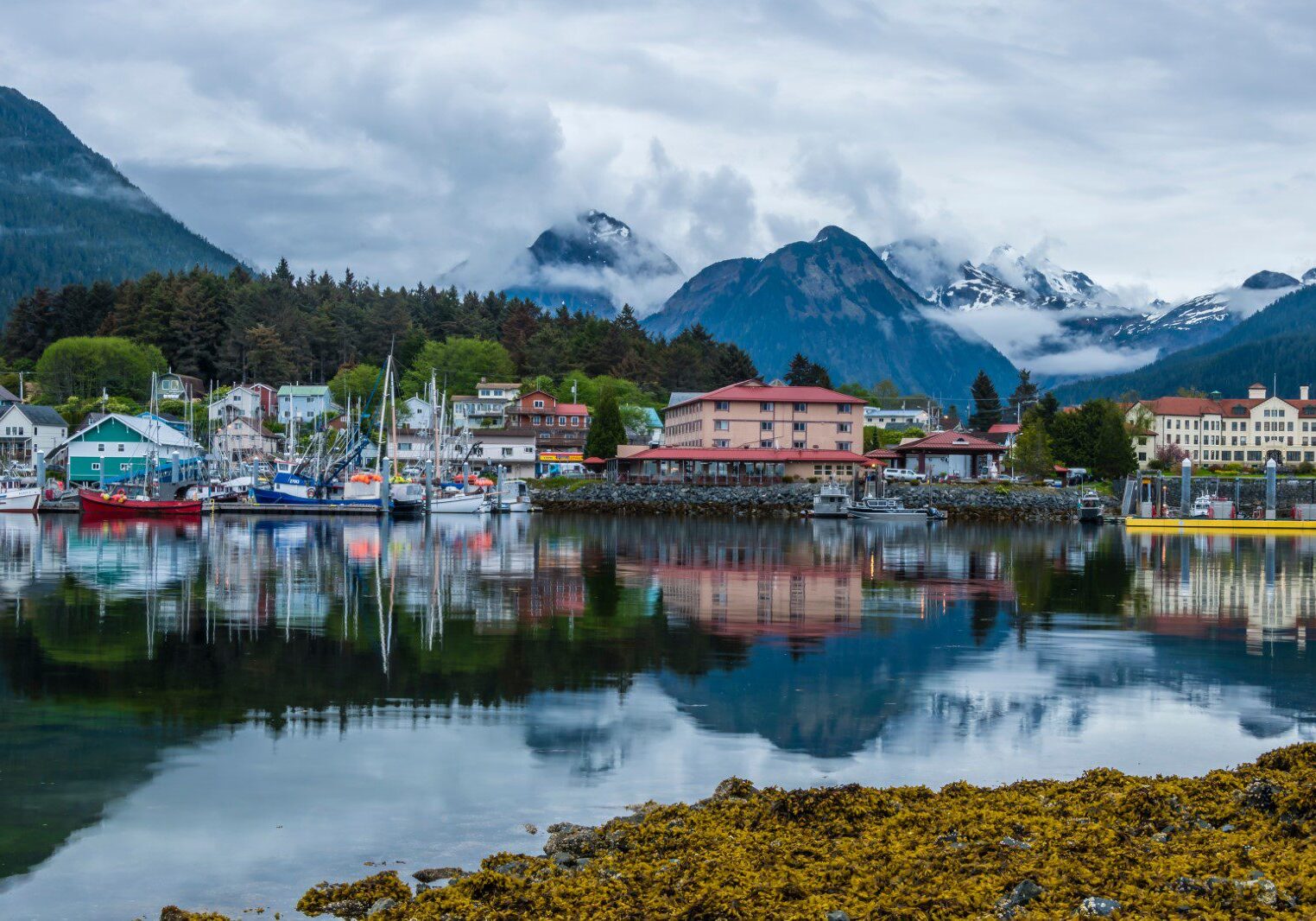 Scenic waterfront town with mountains and cloudy sky reflection.